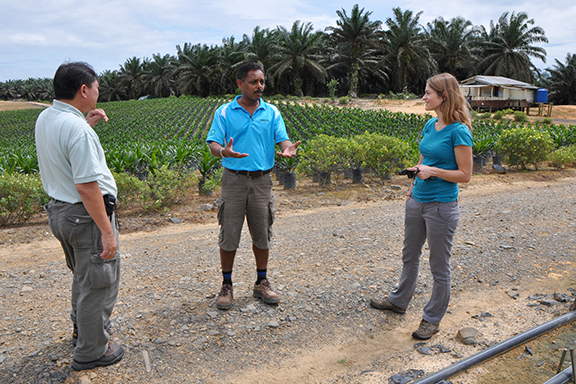 A researcher talking with two farmers from a rural tropical village